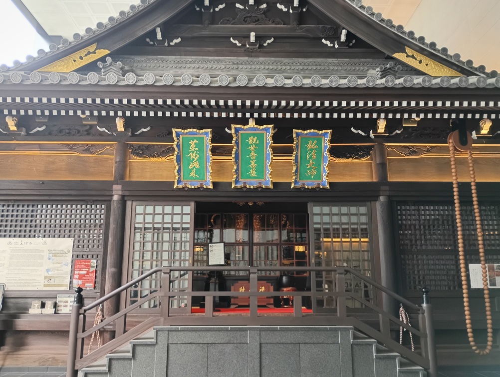 三津寺の本堂外観。江戸時代再建の木造建築が現代のビルに包まれるように佇む