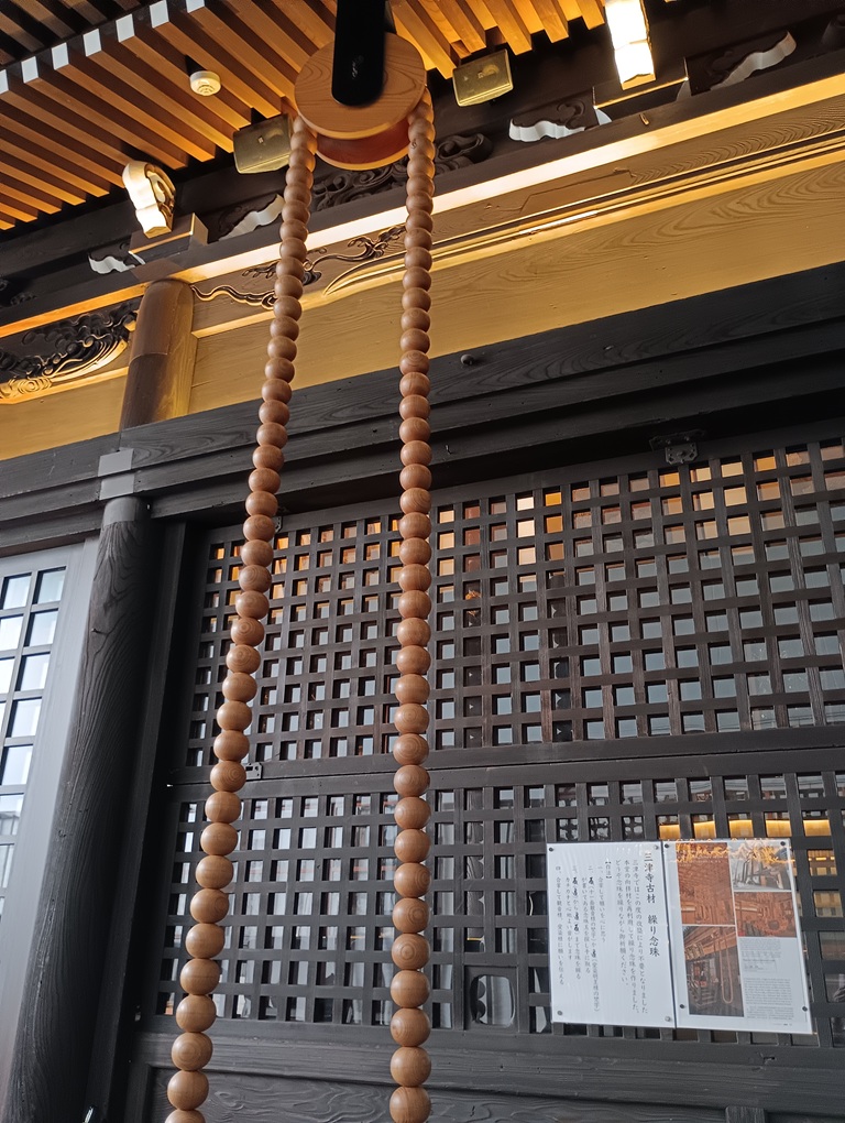 三津寺の境内に設置された操り念珠。参拝者が数珠を回して祈りを捧げる様子