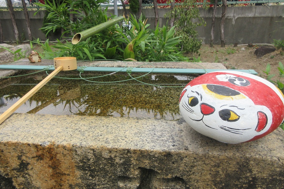 手水舎の縁にちょこんと座るネコの置物。