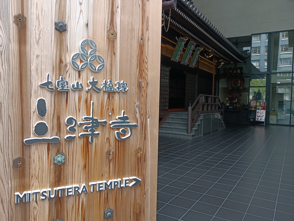 大阪・心斎橋にある三津寺。近代的なビルのエントランス越しに、江戸時代再建の本堂が少し見える。都会と歴史が共存する寺院の姿